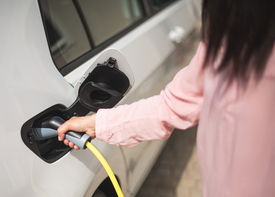 Woman charging a electric car at a charging station